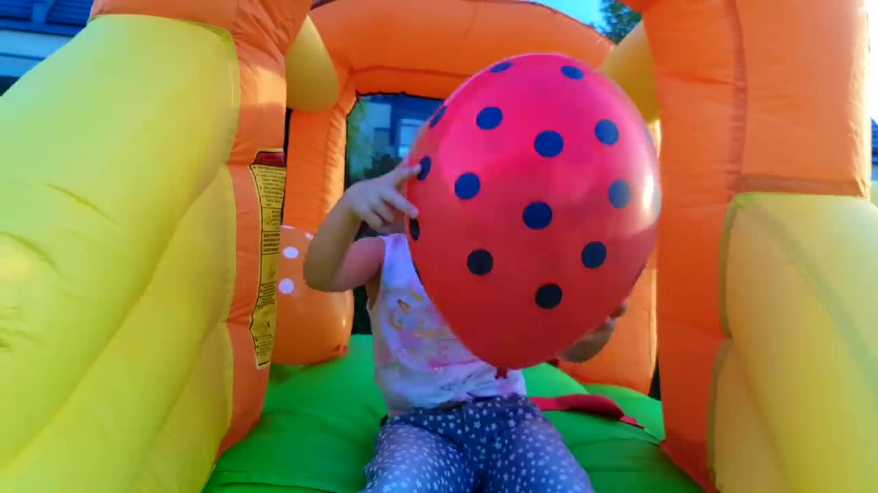 Watch this cute little girl having a wonderful time in a vibrant bounce house! She’s busy playing with her bright red polka dot balloon—so many happy giggles and playful moments! 👧🎈❤️
