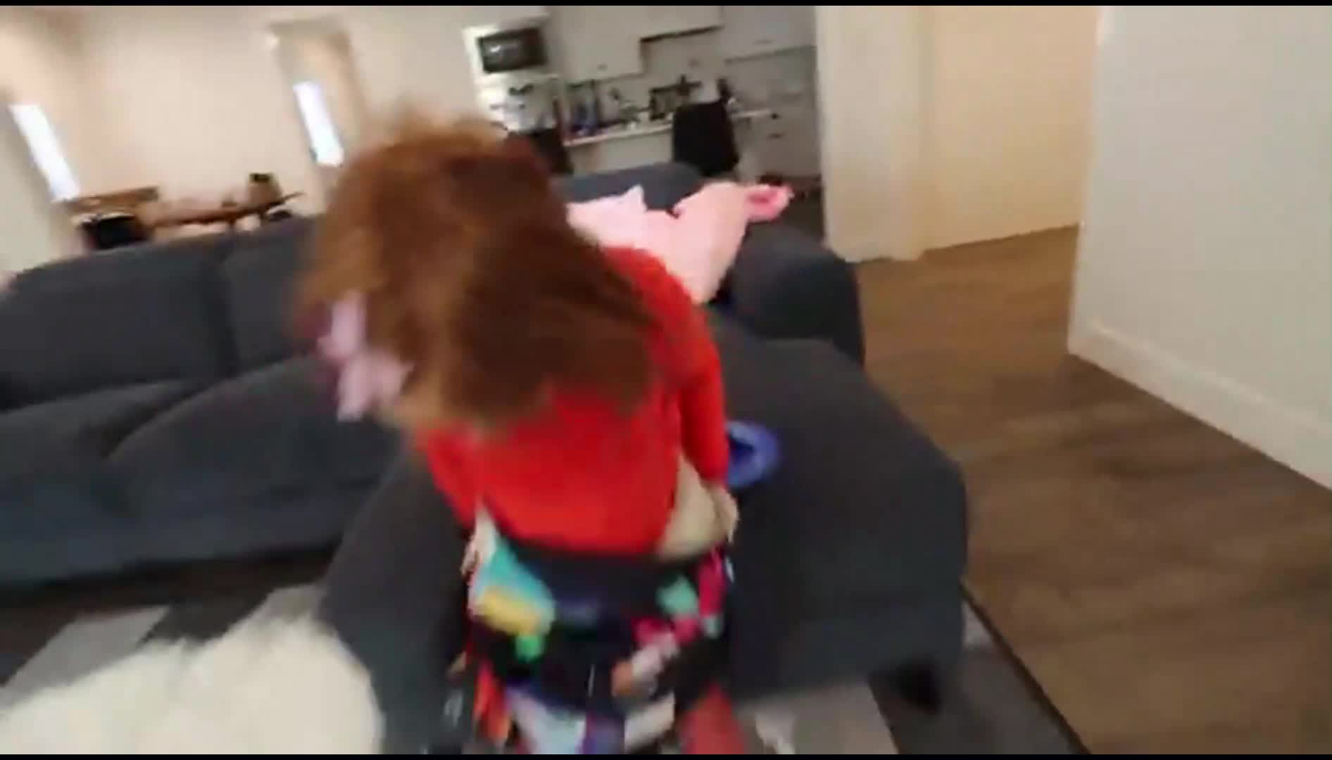 Watch this adorable little girl with red hair having fun at home! She's wearing a bright red top and a colorful skirt, playing with toys on the couch. So heartwarming and full of joy! 😊🧸