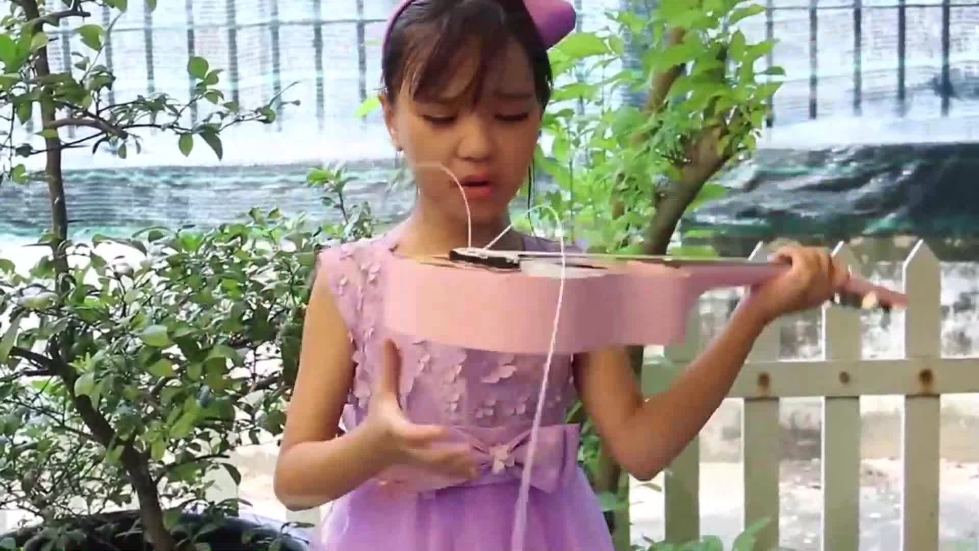 A sweet little girl in a pretty purple dress with a bow in her hair is singing and playing her pink guitar outdoors! 🌿 She looks so happy making music in the fresh air, surrounded by green plants and a white fence. A heartwarming scene for music lovers and kids! 🎤✨