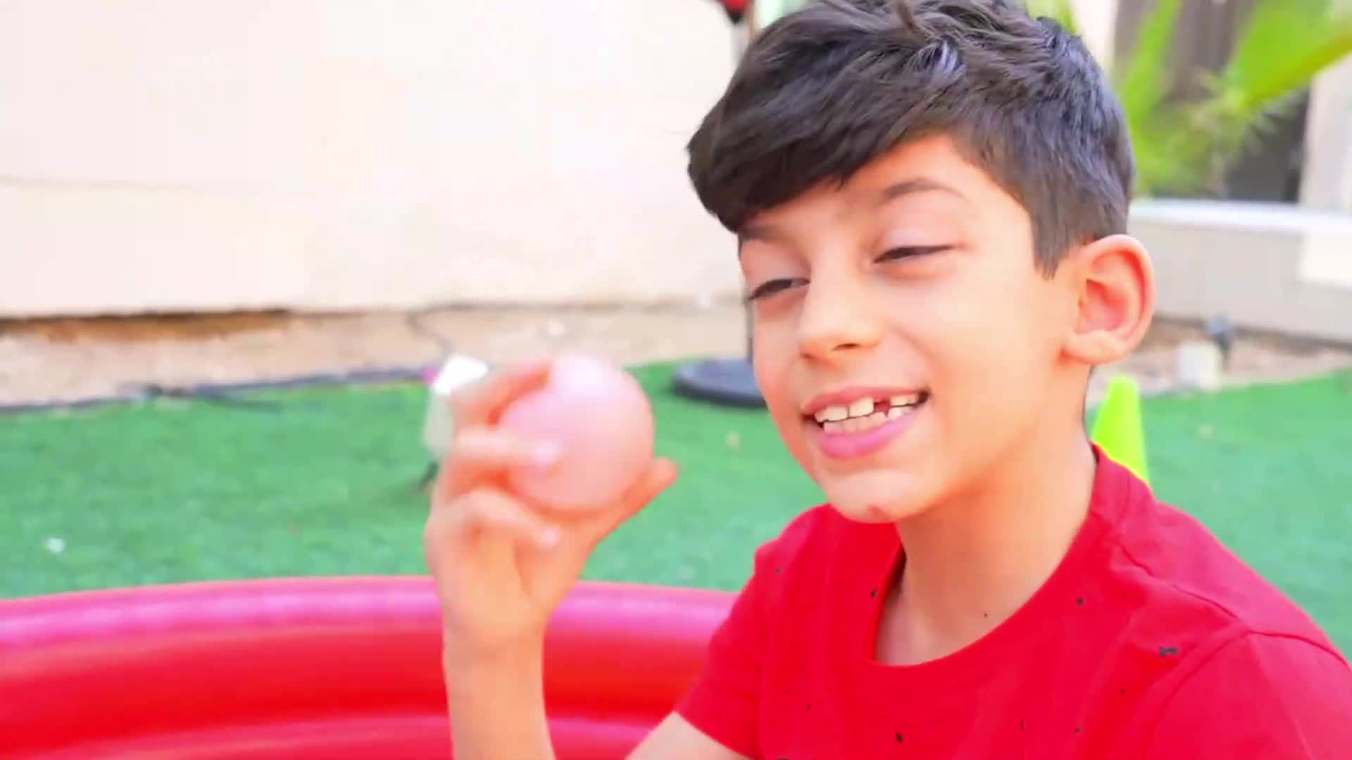 A happy little boy plays with a pink balloon near a red inflatable pool in the backyard! He looks so joyful, enjoying the sunny day with his colorful balloon. Perfect for summer fun and playful moments! 😊