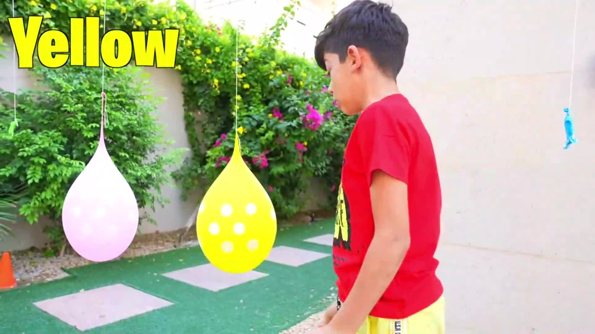 A little boy is having fun learning colors with colorful water balloons! There are pink and yellow water balloons hanging, and he might be trying to pop them or identify the colors. It's a fun and colorful activity for kids to learn about different hues! ๐ง๐ค