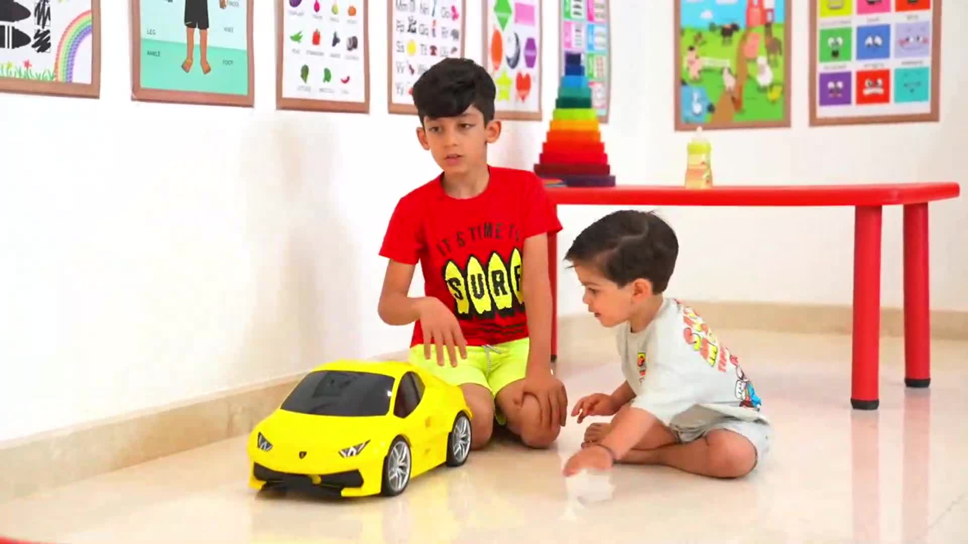 Two little boys are having a wonderful time playing with a cool yellow toy car in a colorful classroom! Theyโre sitting on the floor, laughing and interacting with the car, surrounded by fun educational posters and toysโsuch a joyful and lively scene of childhood play! ๐โจ