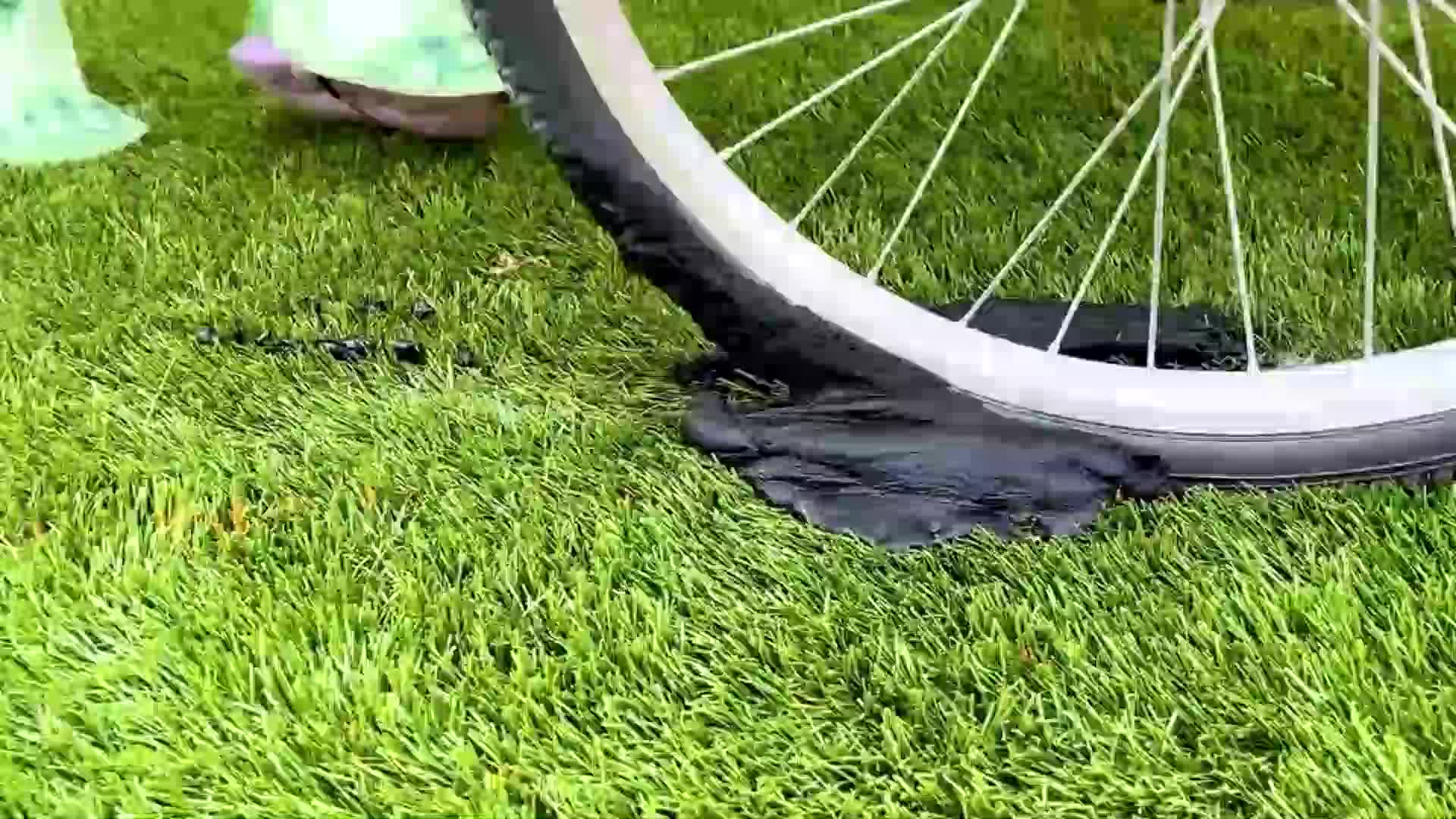 A cute scene of a bike tire leaking black air on green grass! There might be a little kid nearby, maybe their bike, making it super relatable and fun for kids. What will they do to fix it? 🚲💦