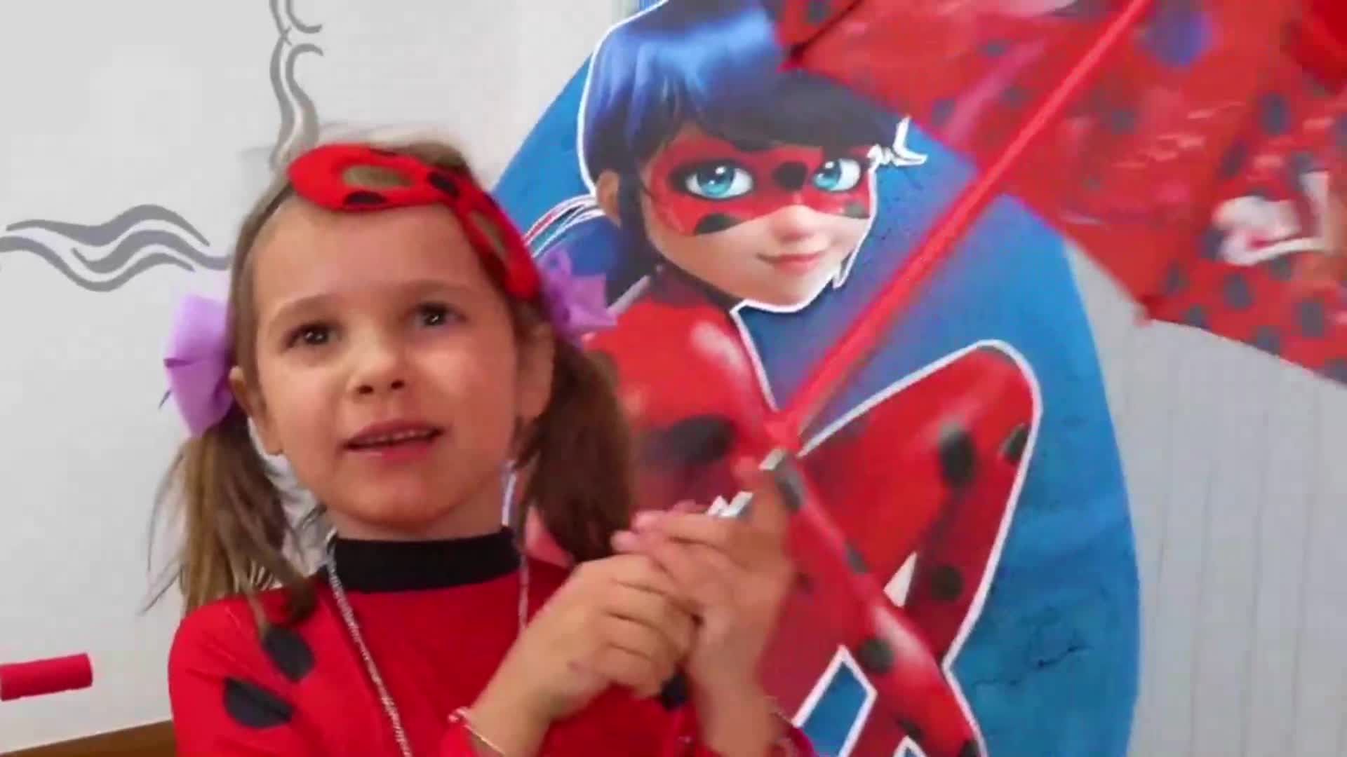 A sweet little girl in a Ladybug costume, wearing a red polka-dot headband and holding a Ladybug-themed prop, with a Ladybug poster behind her! 🎀 She looks so excited and ready to play! 🎉❤️
