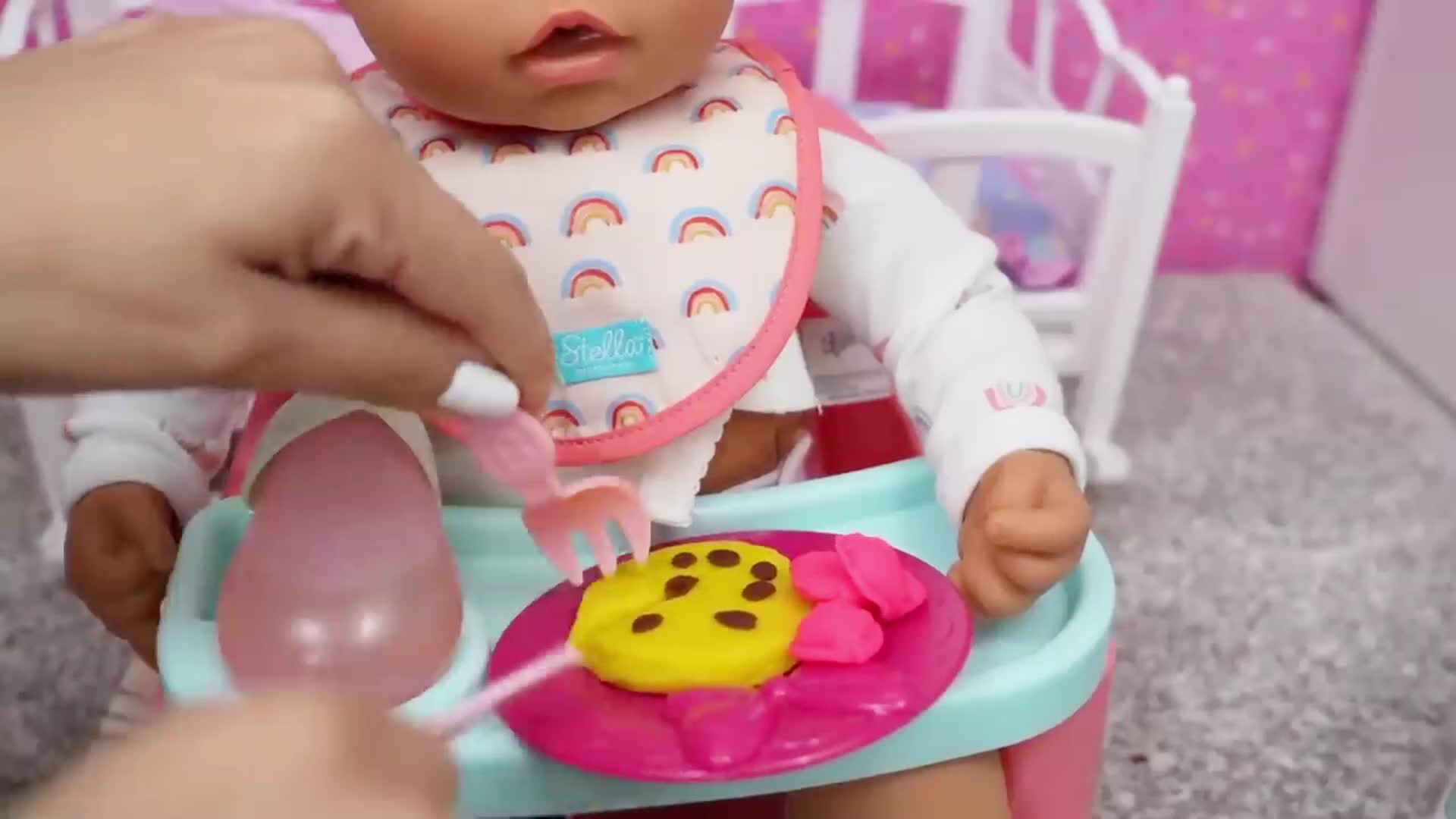 Watch me take care of my baby doll by feeding her delicious pretend cookies! 🍪✨ She's sitting in her high chair, wearing a rainbow-patterned bib, and I use a tiny pink fork to give her a yellow cookie with chocolate dots. It's such a fun and sweet pretend play activity for little kids! 👶🍼 #BabyDollFun #PretendPlayTime