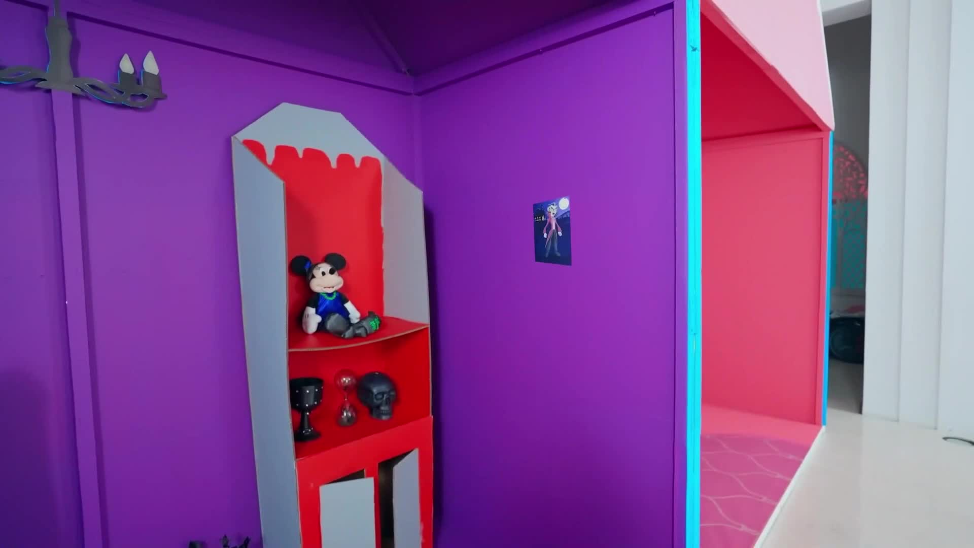 A colorful, creative playhouse with purple walls and pink accents! 🎨 On the red shelf, a cute Mickey Mouse plush sits alongside tiny skulls and goblets—spooky yet playful! 👻✨ Perfect for little ones to imagine magical adventures!",