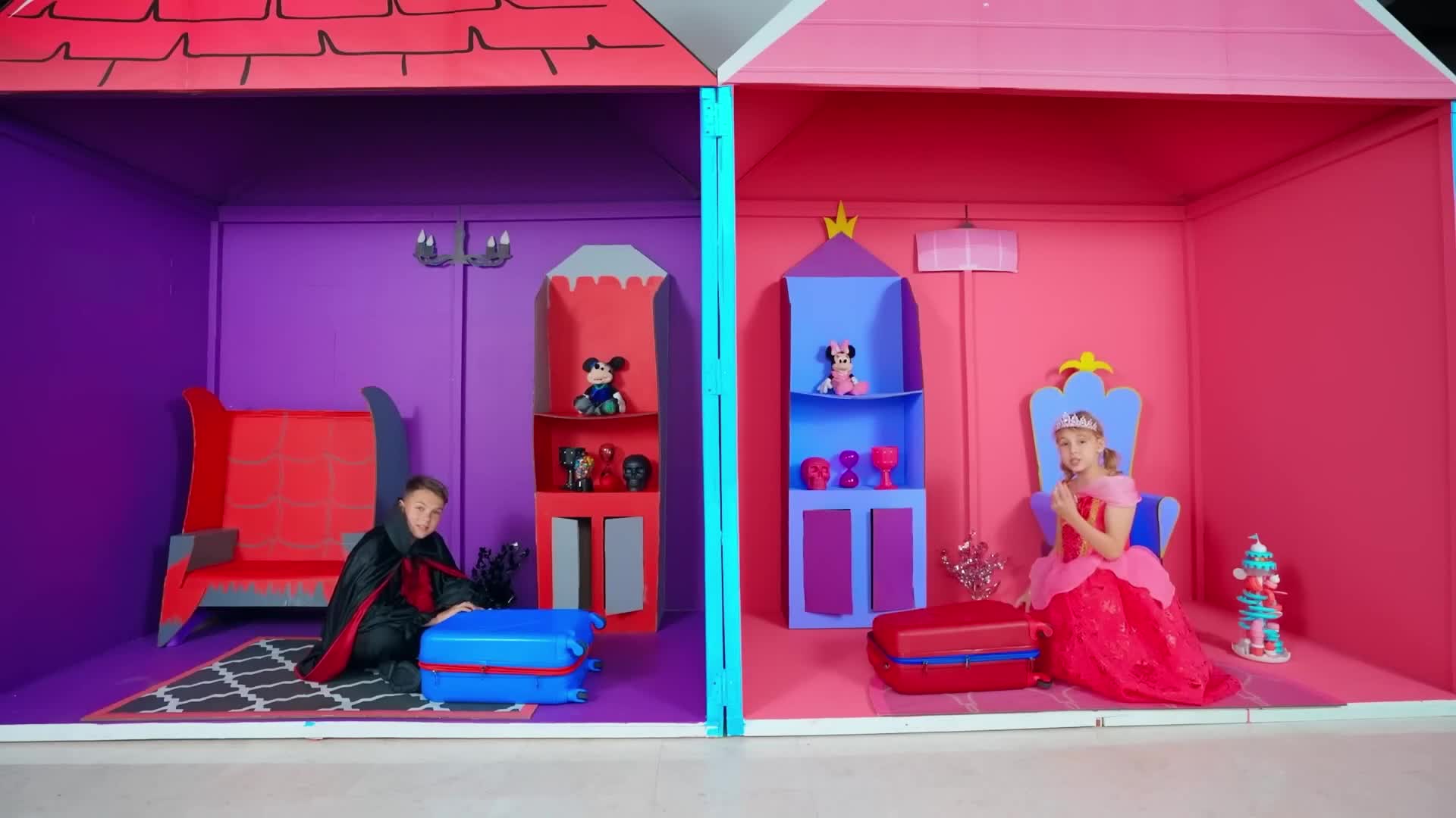 Two little ones are having a blast with role play! One’s a spooky vampire 🧛‍♂️ in a purple castle room with a blue suitcase and Mickey Mouse toys, and the other’s a sparkly princess 👑 in a pink fairy-tale castle with a red suitcase, a crown, and a cute cupcake decoration! They’re exploring their magical playhouse—what fun will they have next? 🏰✨